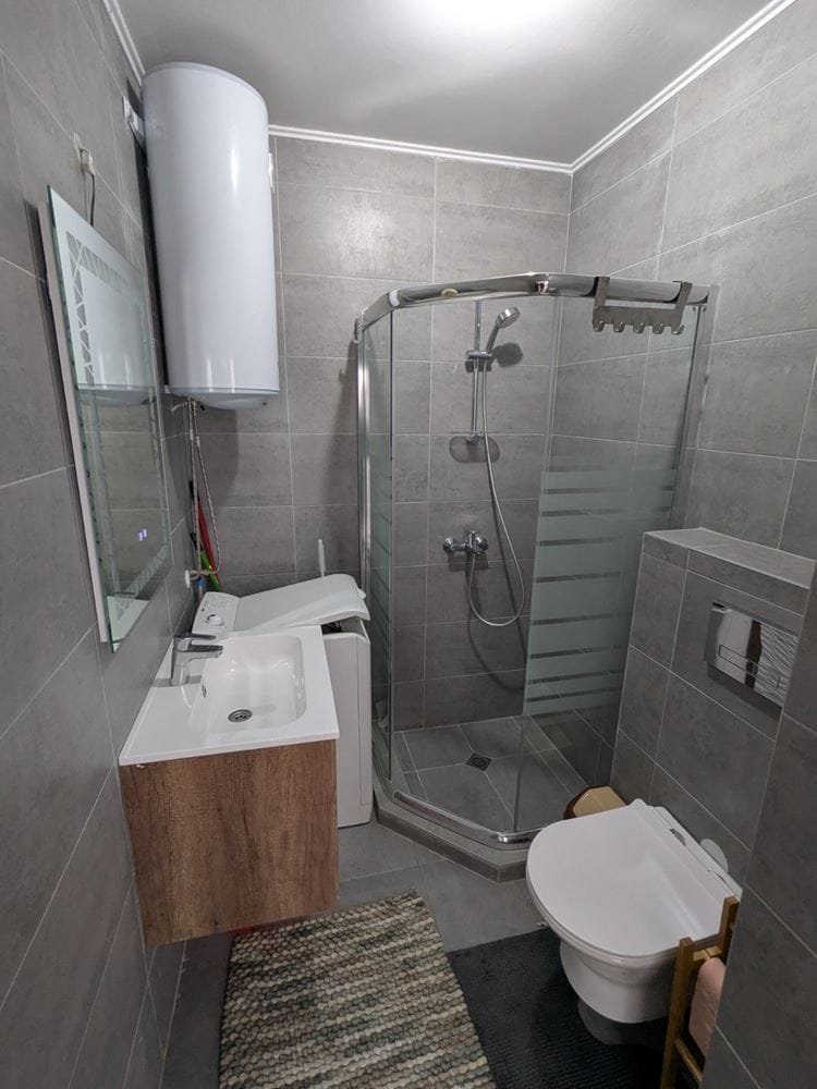 Современная ванная комната с душевой кабиной, туалетом, раковиной и стильной отделкой в нейтральных тонах.