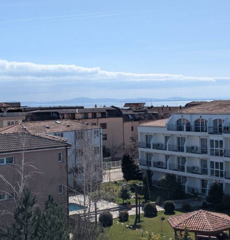 Двухкомнатный апартамент с видом на море и крыши зданий, зеленый двор с растениями и прогулочными дорожками.