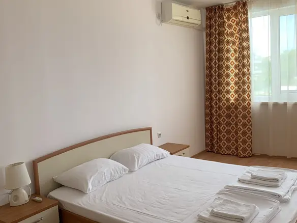 Двухкомнатный апартамент с кроватью, светлыми стенами и окнами, оформленный в современном стиле.