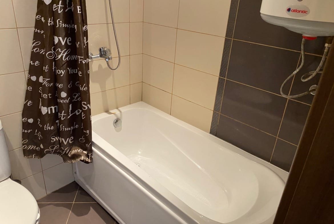 Ванная комната в трехкомнатном апартаменте с ванной, душем, и занавеской коричневого цвета на фоне плитки.