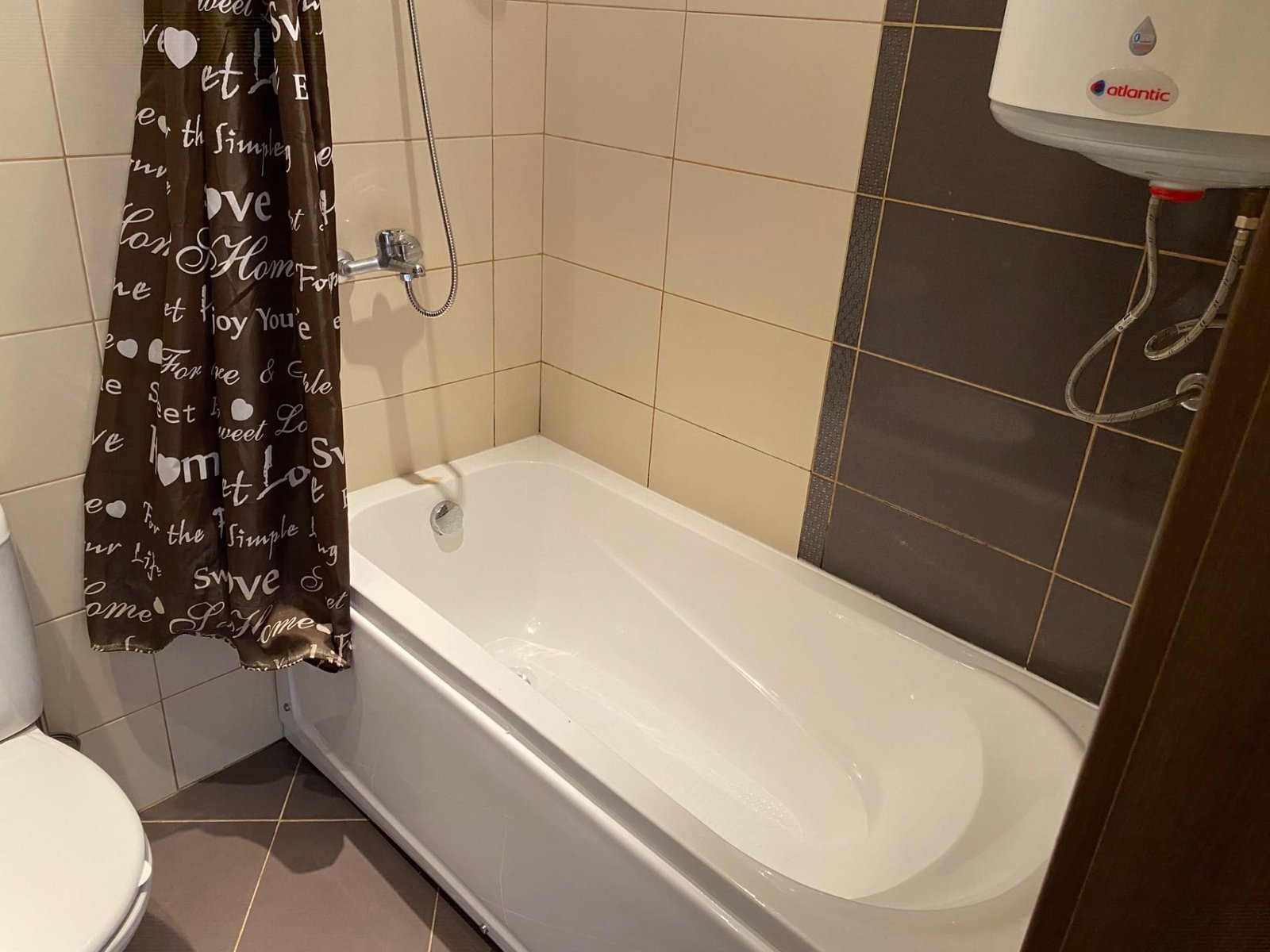 Ванная комната в трехкомнатном апартаменте с ванной, душем, и занавеской коричневого цвета на фоне плитки.