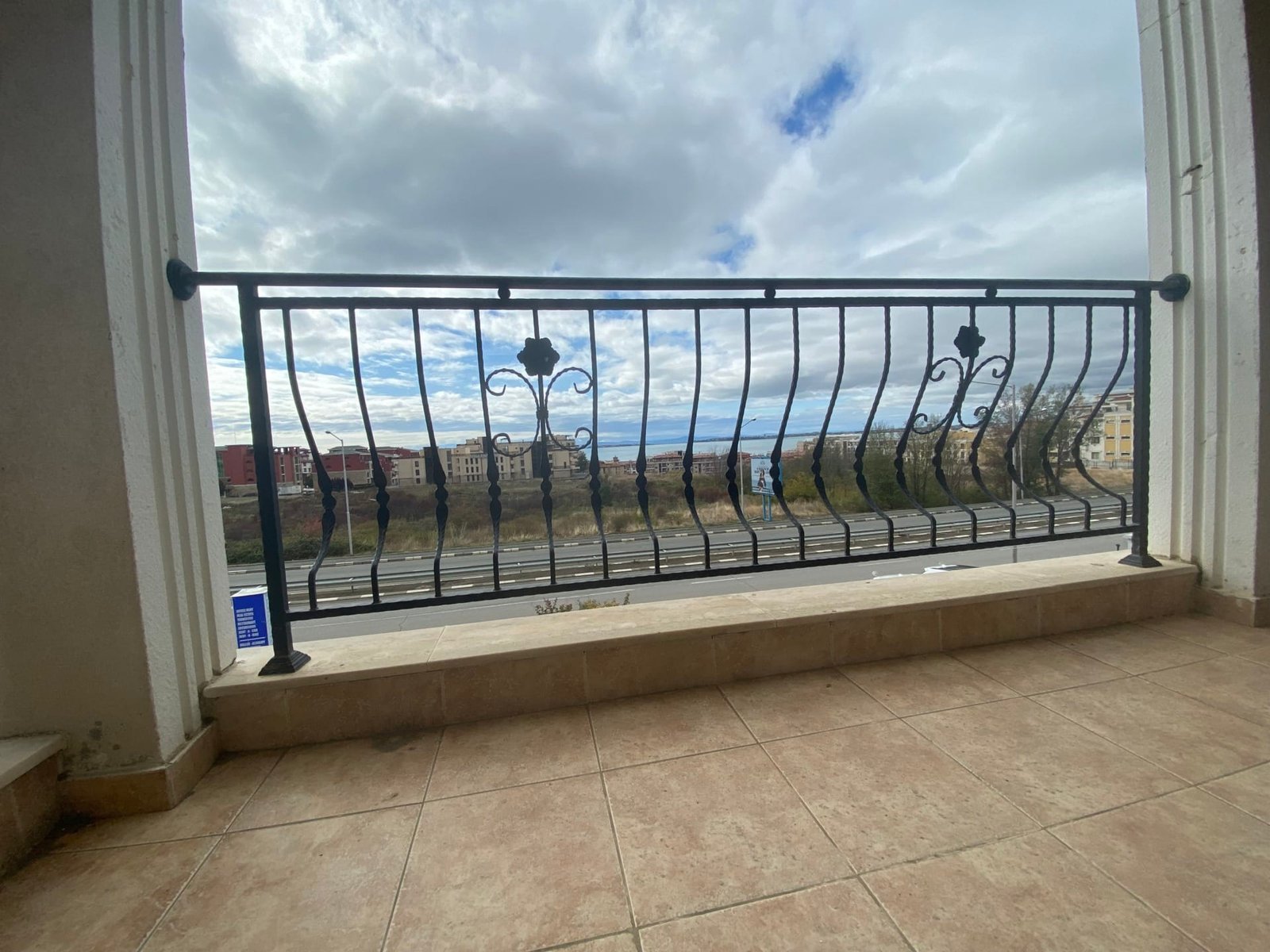 Балкон с металлическим ограждением, панорамный вид на город и небо, плитка на полу. Подходит для жилья в комплексе Macon Residence.