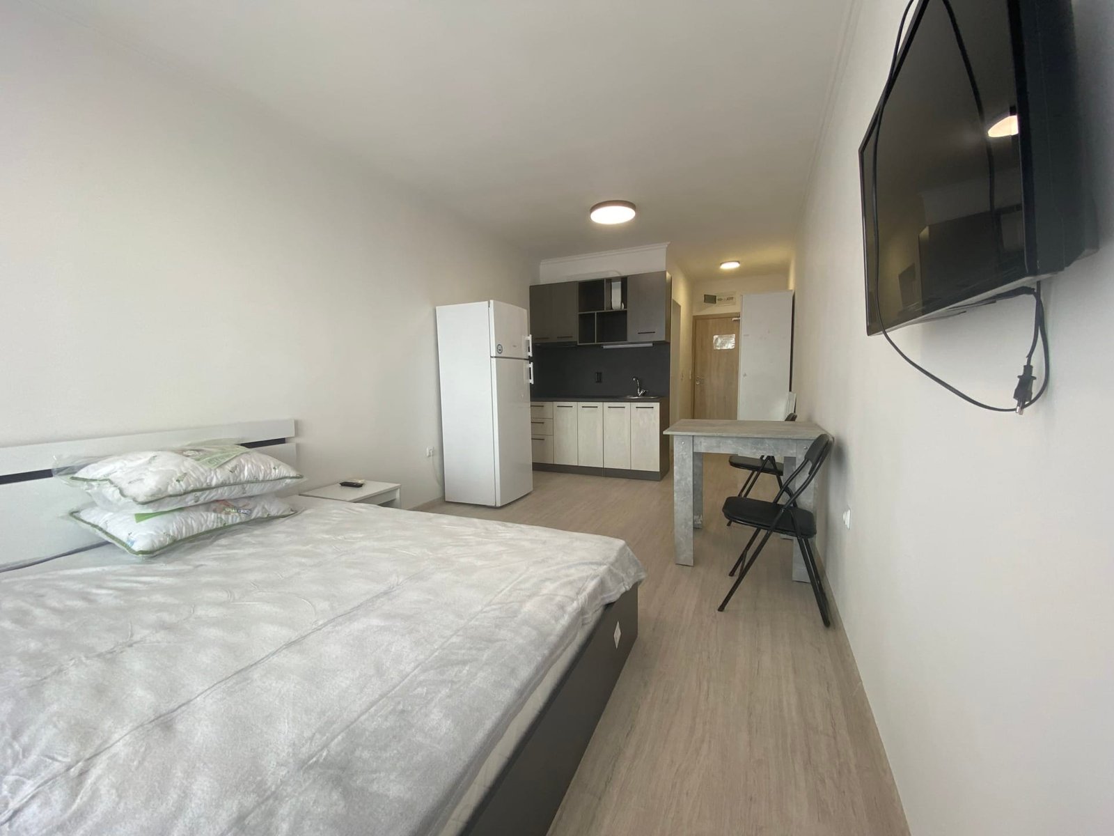 Современная студия с двуспальной кроватью, кухней, стиральной машинкой и телевизором в комплексе Macon Residence.