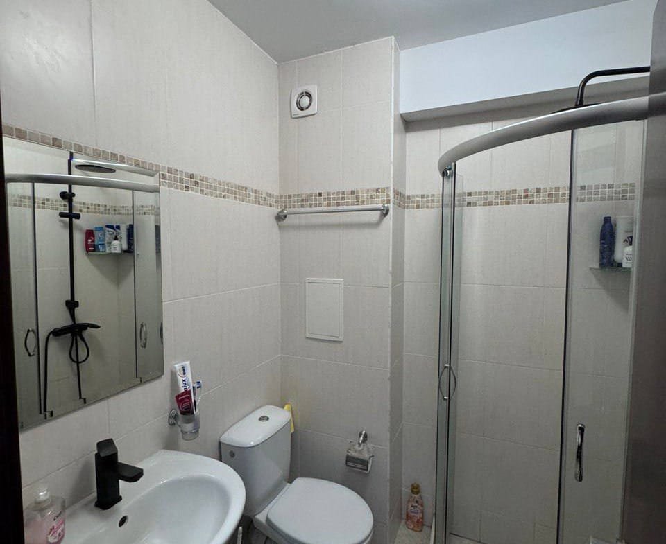 Современная ванная комната с душевой кабиной, унитазом и раковиной, оформленная в светлых тонах.