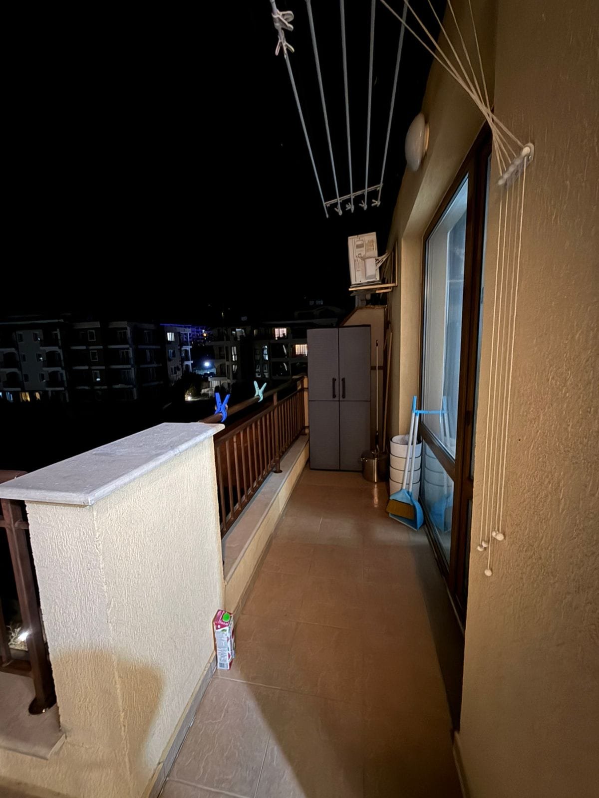 Уютный балкон с окнами, шкафом и чистым полом, атмосфера спокойной ночи с мягким освещением.