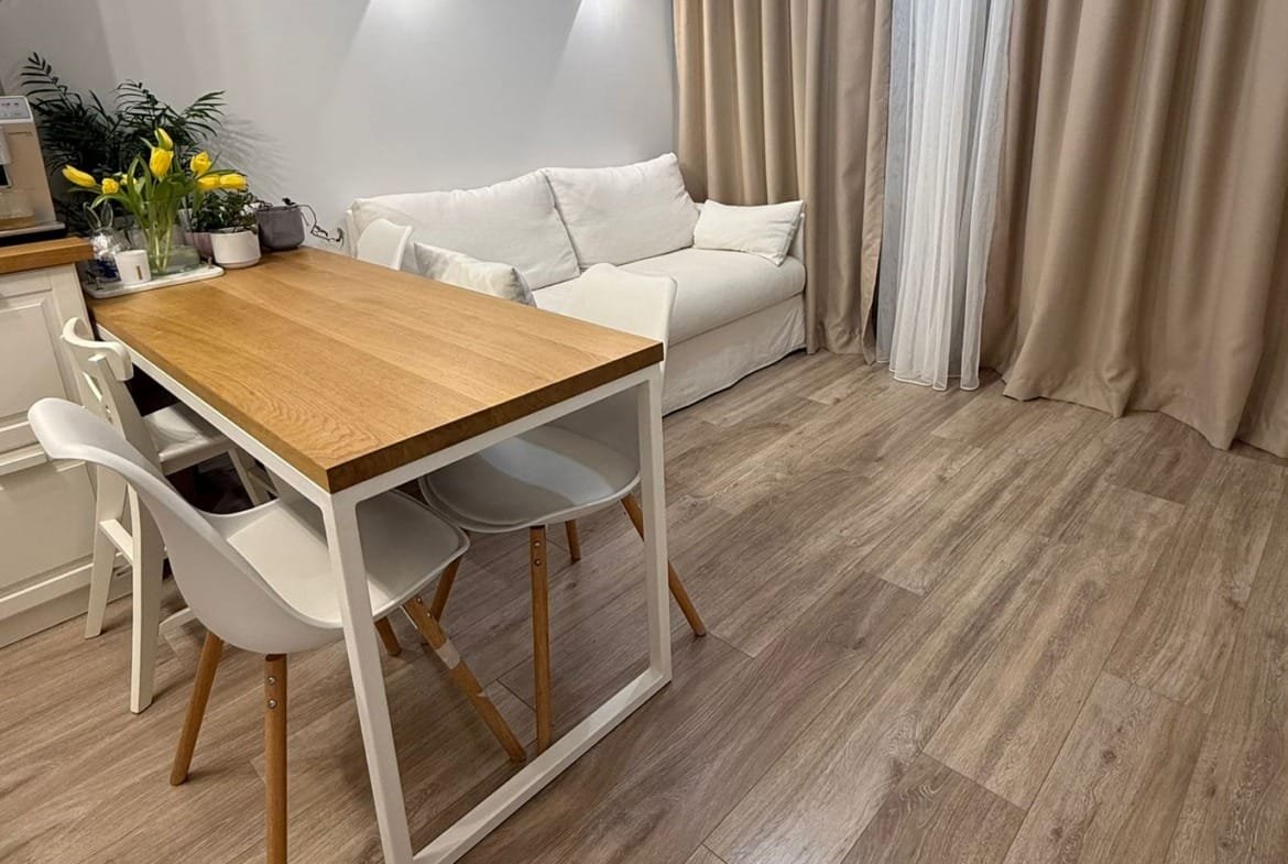 Современный интерьер двухкомнатного апартамента с обеденным столом, диваном и воздухом, освещённый мягким светом.