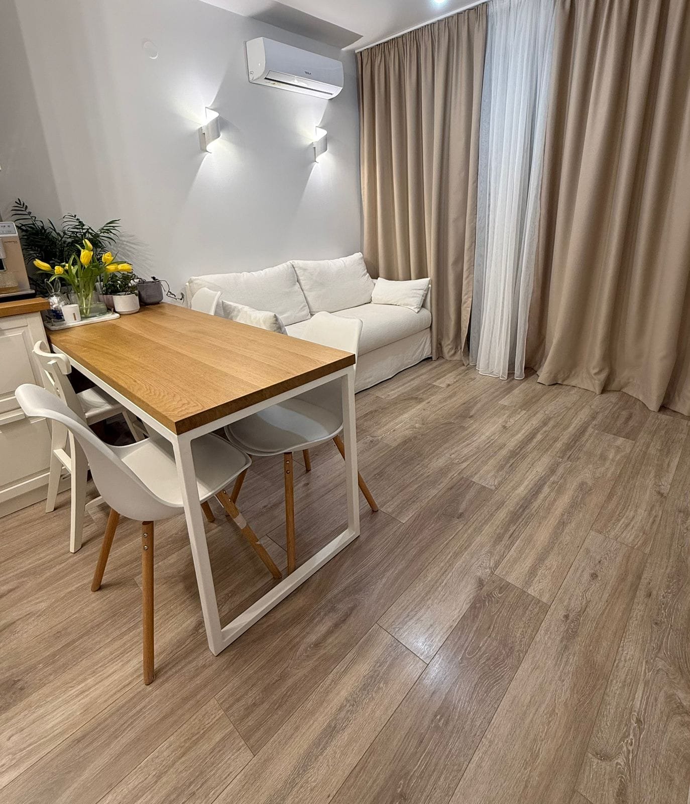 Современный интерьер двухкомнатного апартамента с обеденным столом, диваном и воздухом, освещённый мягким светом.