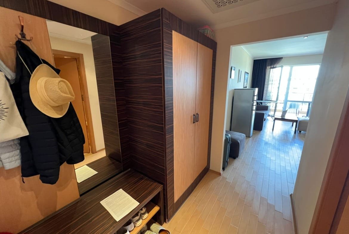 Современный интерьер коридора квартиры в Болгарии с шкафом, вешалкой и выходом в гостиную. Подходит для продажи недвижимости.