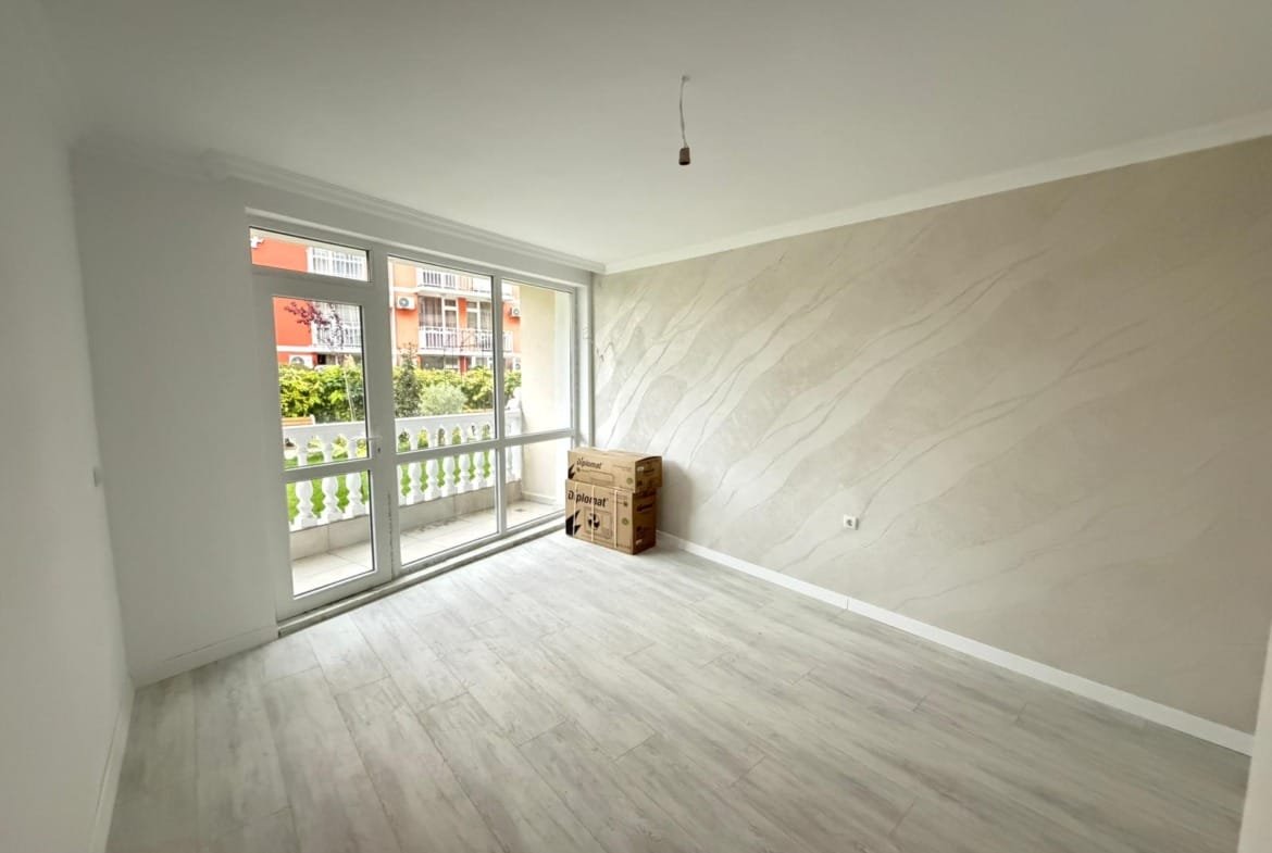 Светлая комната с большими окнами и только что доставленными коробками, готова для обустройства в недвижимости Болгарии.