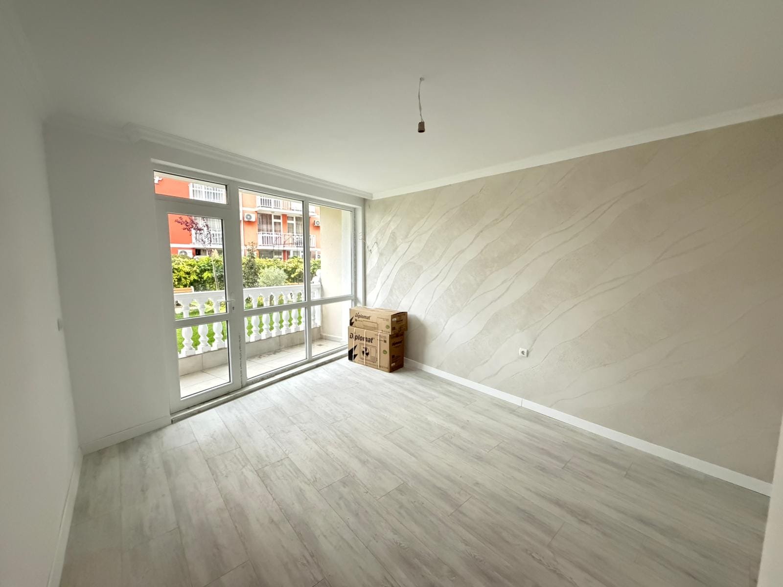 Светлая комната с большими окнами и только что доставленными коробками, готова для обустройства в недвижимости Болгарии.