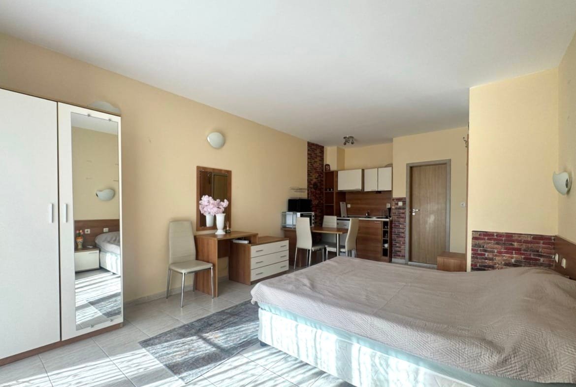 Компактная квартира-студия в Болгарии с кухней, обеденной зоной, дверью в ванную и светлыми тонами. Подходит для отдыха и жизни.