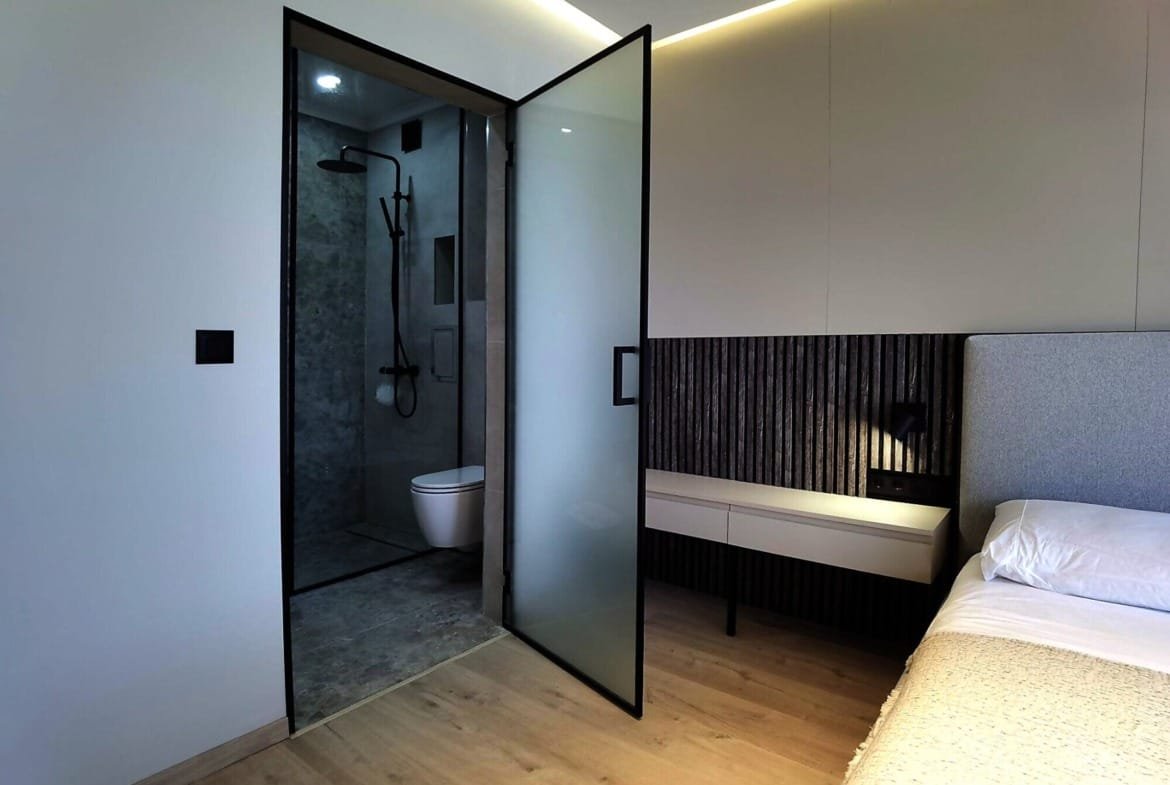 Современная спальня с душевой кабиной и тоалетом, светлые тона интерьера, стильный дизайн для комфортного проживания в Болгарии.