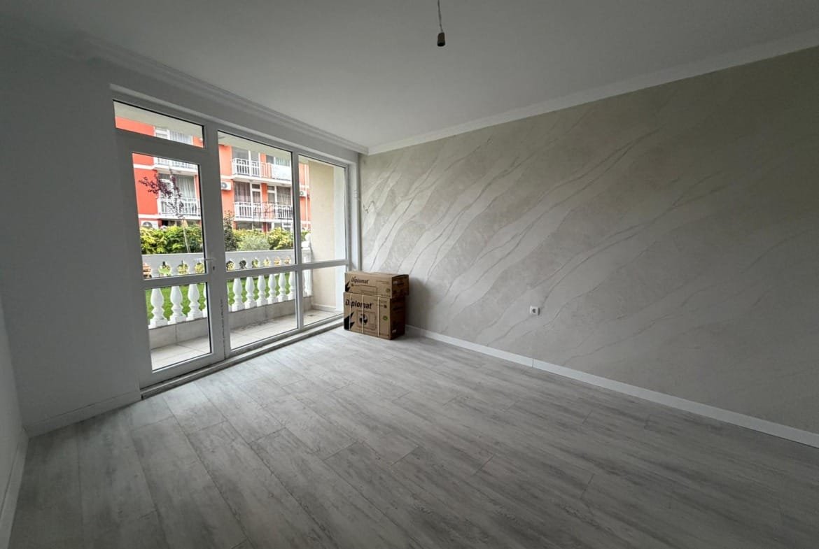 Современная квартира в Болгарии с большими окнами, светлыми стенами и видом на зеленый двор. Подготовка к продаже.