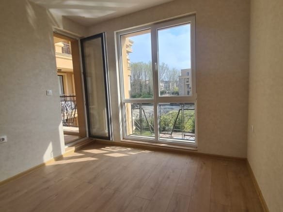 Светлая комната с большими окнами, выходящими на балкон, идеальна для покупки недвижимости в Болгарии.