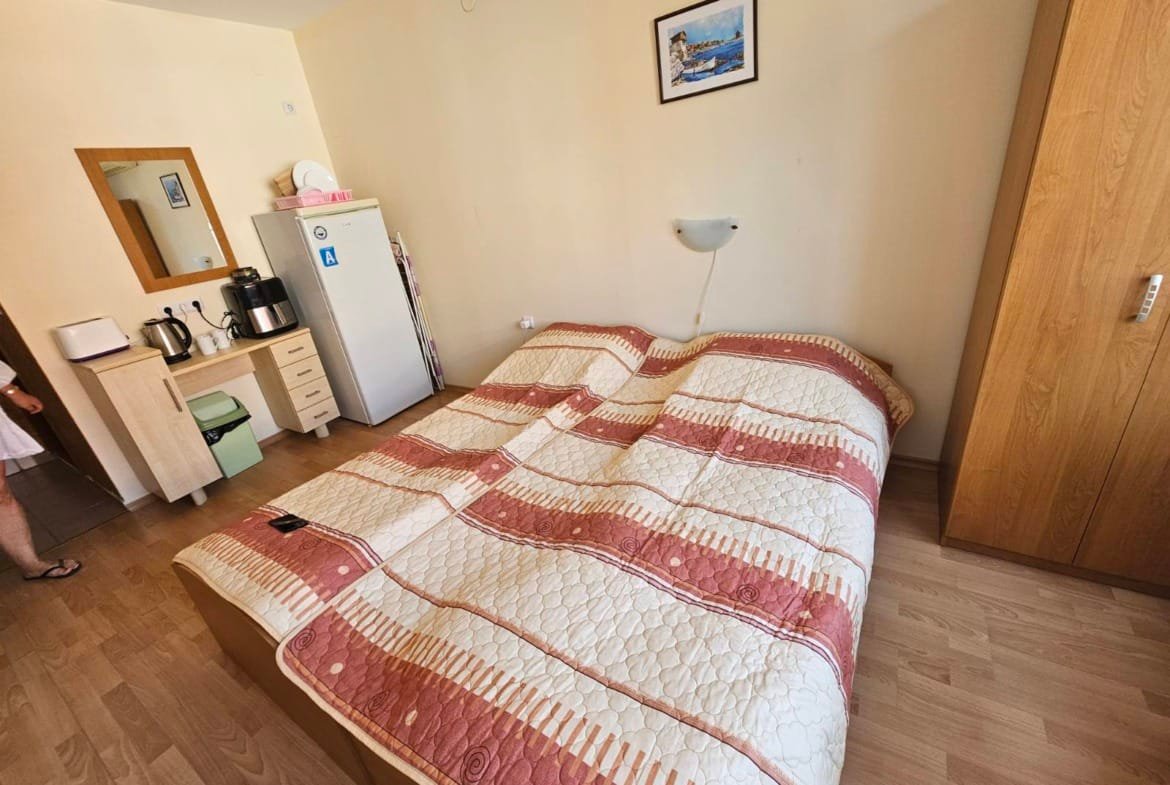 Уютная спальня с двуспальной кроватью, шкафом и холодильником, идеальная для проживания в Болгарии.