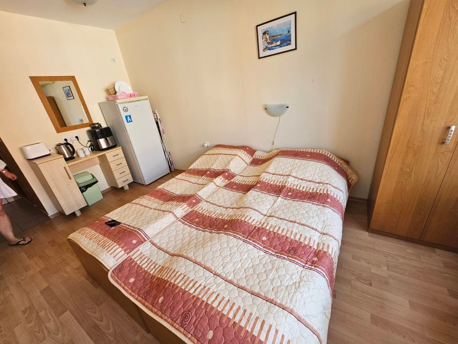 Уютная спальня с двуспальной кроватью, шкафом и холодильником, идеальная для проживания в Болгарии.