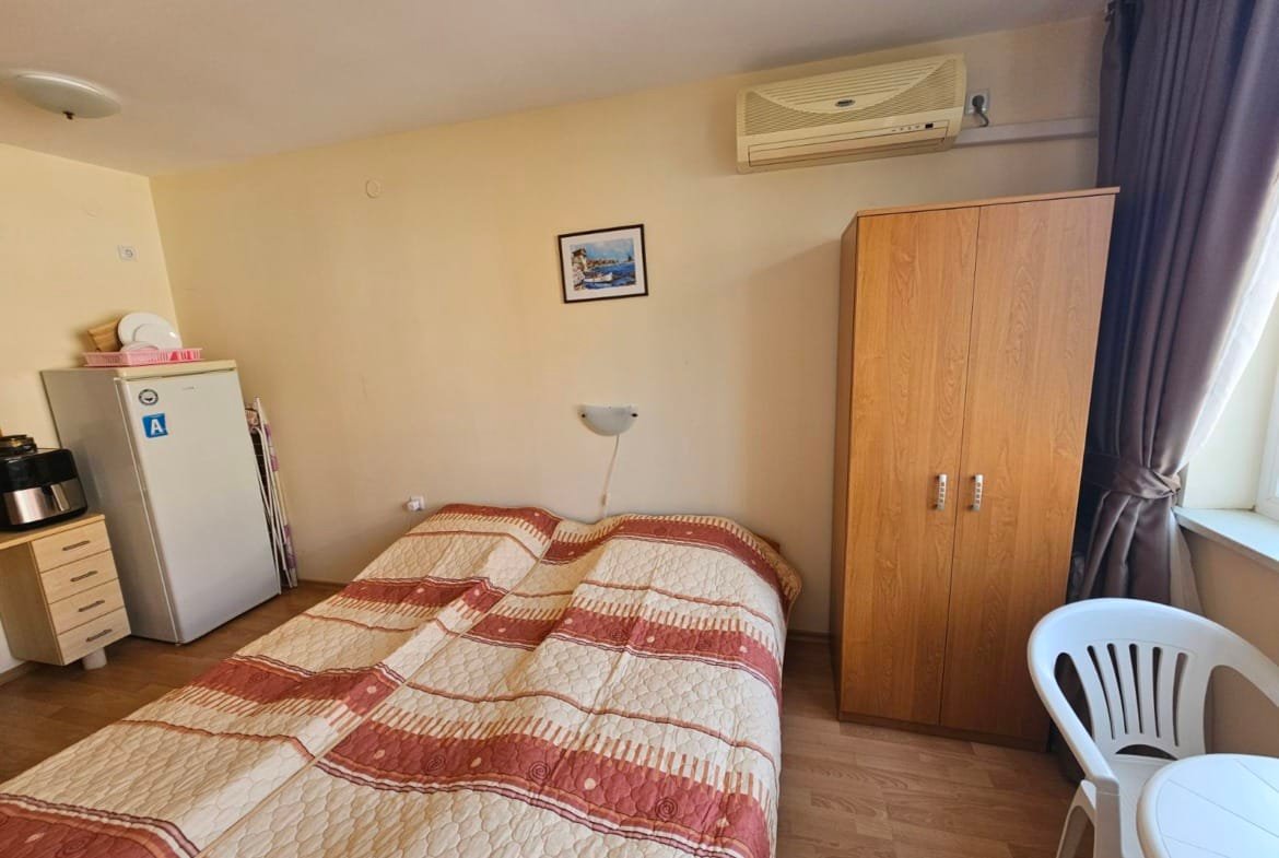 Уютный номер с двуспальной кроватью, шкафом, холодильником и светлым интерьером, идеальный для отдыха в Болгарии.