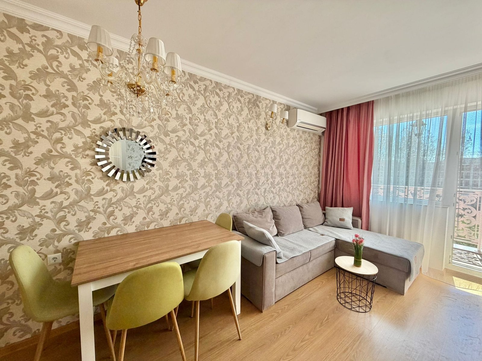 Современная гостиная с диваном, обеденным столом и стульями, оформленная в светлых тонах, идеальная для покупки недвижимости в Болгарии.