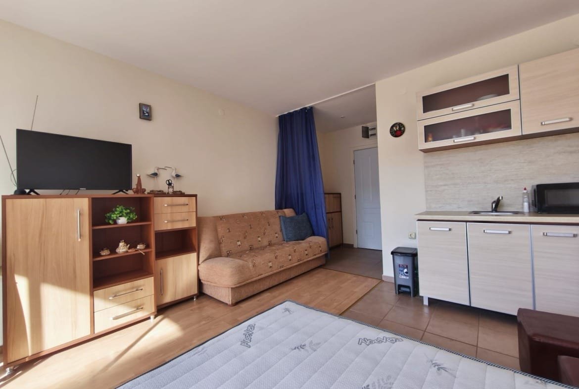 Современная квартира в Болгарии с уютным интерьером, диваном, кухонным гарнитуром и телевизором. Идеально для покупки или аренды.