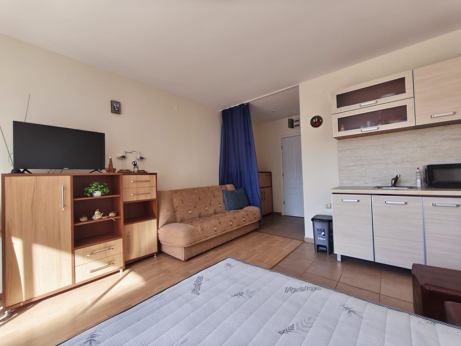 Уютная квартира-студия с кухней и диваном Современная квартира в Болгарии с уютным интерьером, диваном, кухонным гарнитуром и телевизором. Идеально для покупки или аренды.