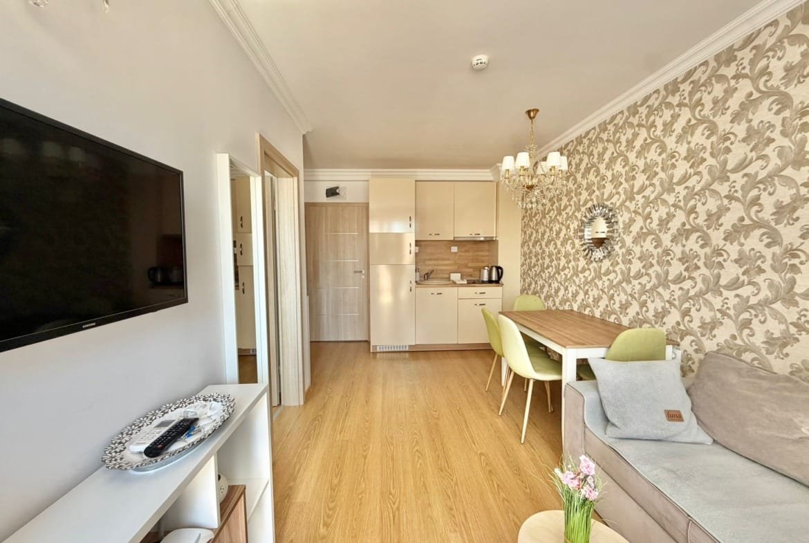 Современный интерьер квартиры в Болгарии с уютной гостиной, кухней и обеденной зоной, оформленный в светлых тонах.