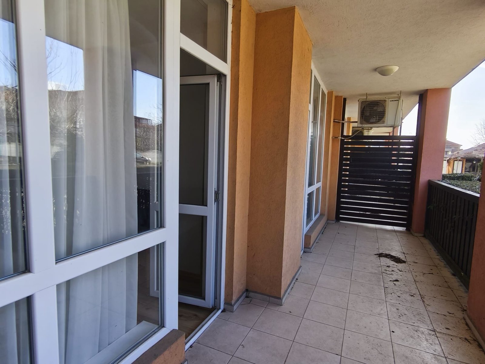 Балкон квартиры с открытым пространством и солнечным светом Балкон квартиры в Болгарии с панорамными окнами, плиточным полом и деревянной перголой, готовый для продажи или аренды.