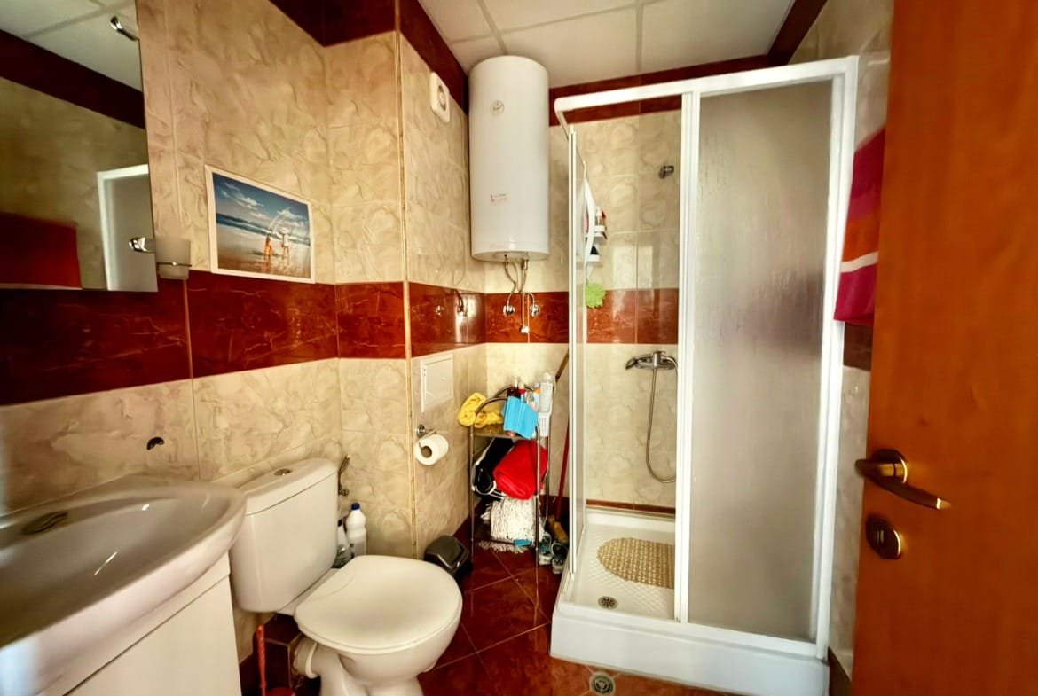 Современная ванная комната с душевой кабиной, унитазом и раковиной, отделанная плиткой в теплом цвете.