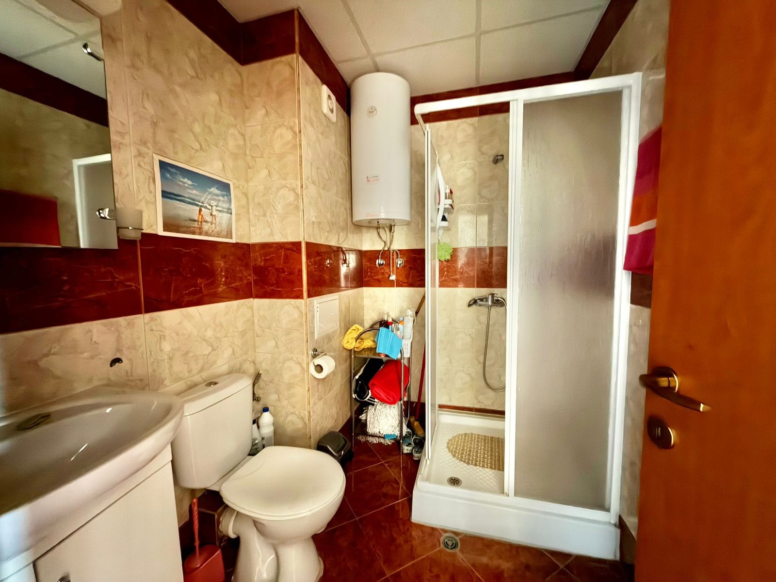 Современная ванная комната с душевой кабиной, унитазом и раковиной, отделанная плиткой в теплом цвете.