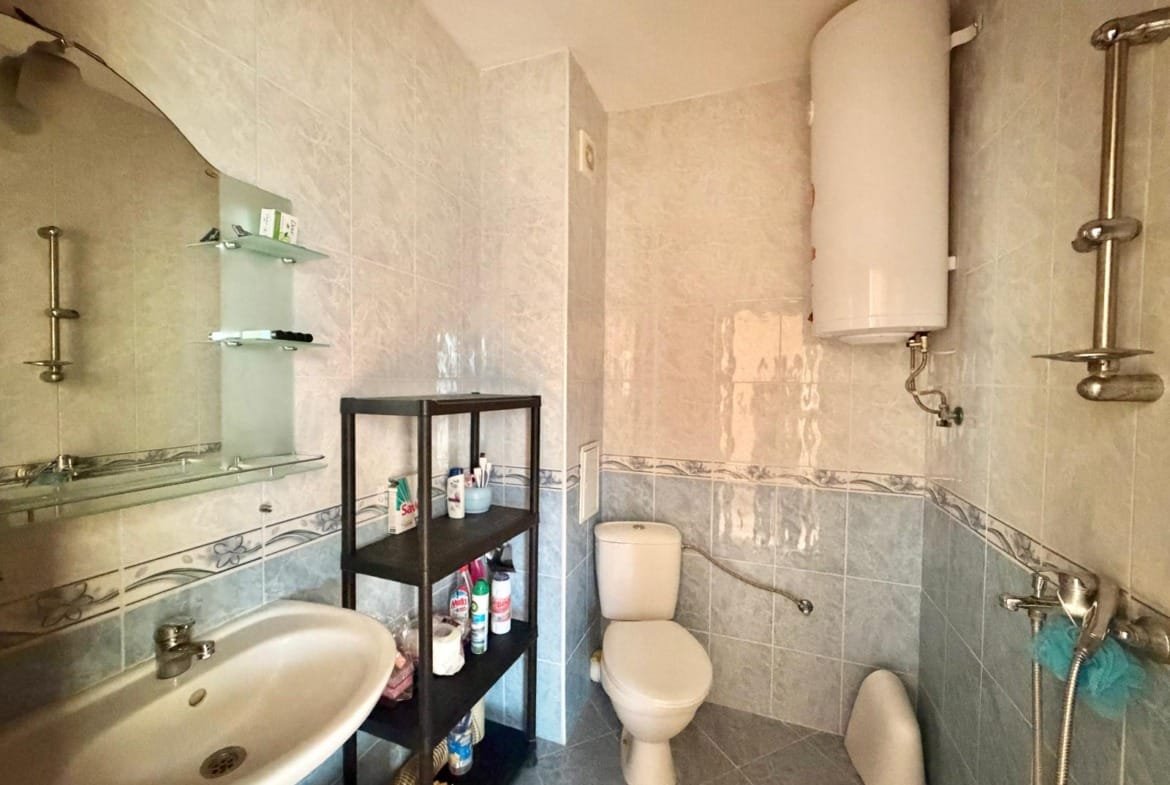 Современная ванная комната с унитазом, раковиной и душевой, отделка в светлых тонах, удобная для продажи недвижимости в Болгарии.