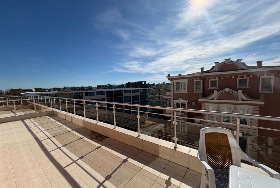 Вид с балкона на жилые здания в Болгарии с ясным небом и солнечным светом, идеальное место для покупки недвижимости.