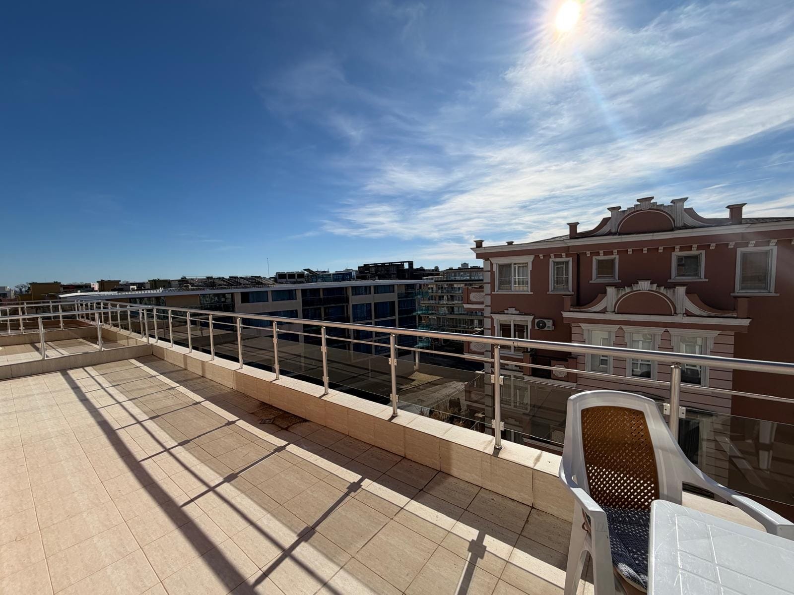 Вид с балкона на жилые здания в Болгарии с ясным небом и солнечным светом, идеальное место для покупки недвижимости.