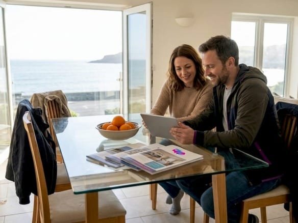 Пара выбирает квартиры у моря, сидя в светлой комнате.