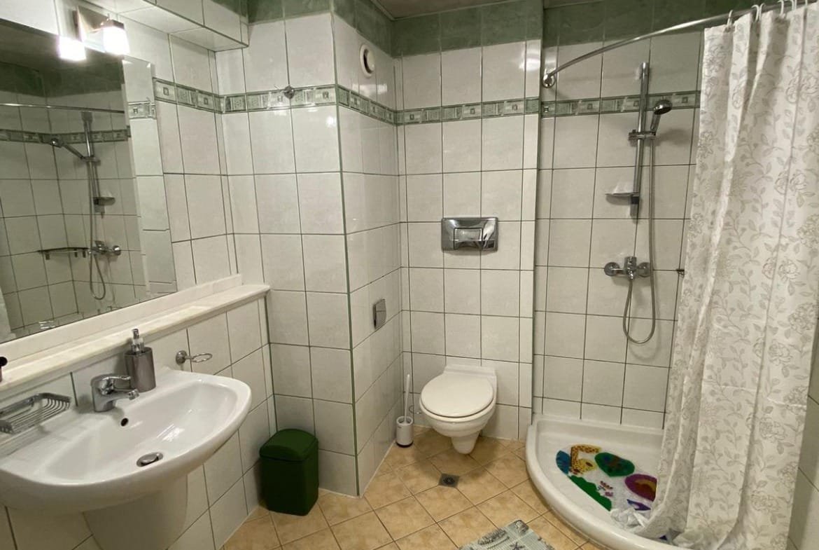 Современная ванная комната в квартире с душевой кабиной, умывальником и плиткой на стенах, подходящая для продажи в Болгарии.