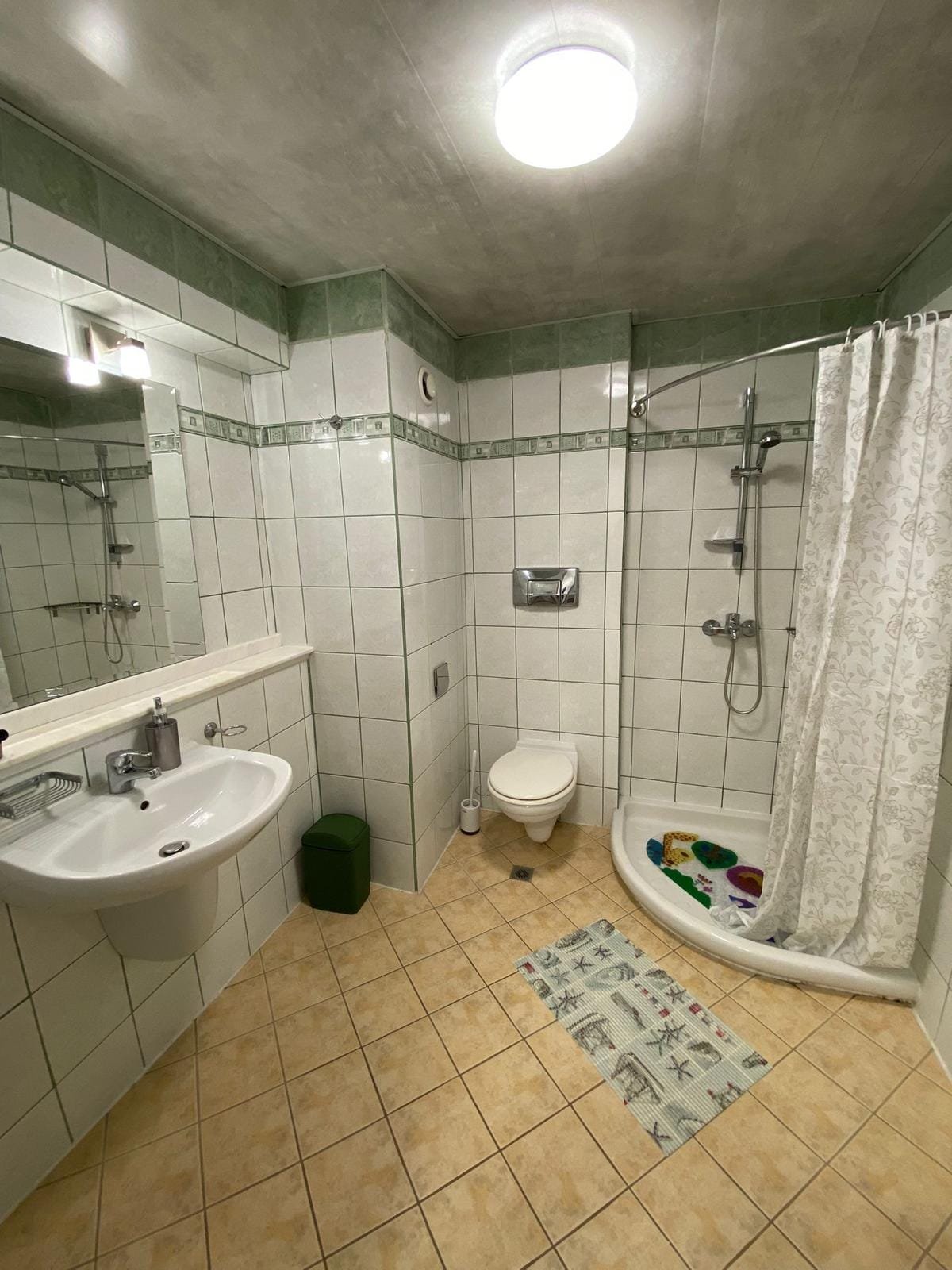 Современная ванная комната в квартире с душевой кабиной, умывальником и плиткой на стенах, подходящая для продажи в Болгарии.