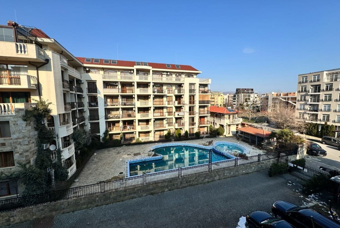 Современный жилой комплекс в Болгарии с бассейном и террасой на фоне ясного неба, идеально подходит для покупки недвижимости.