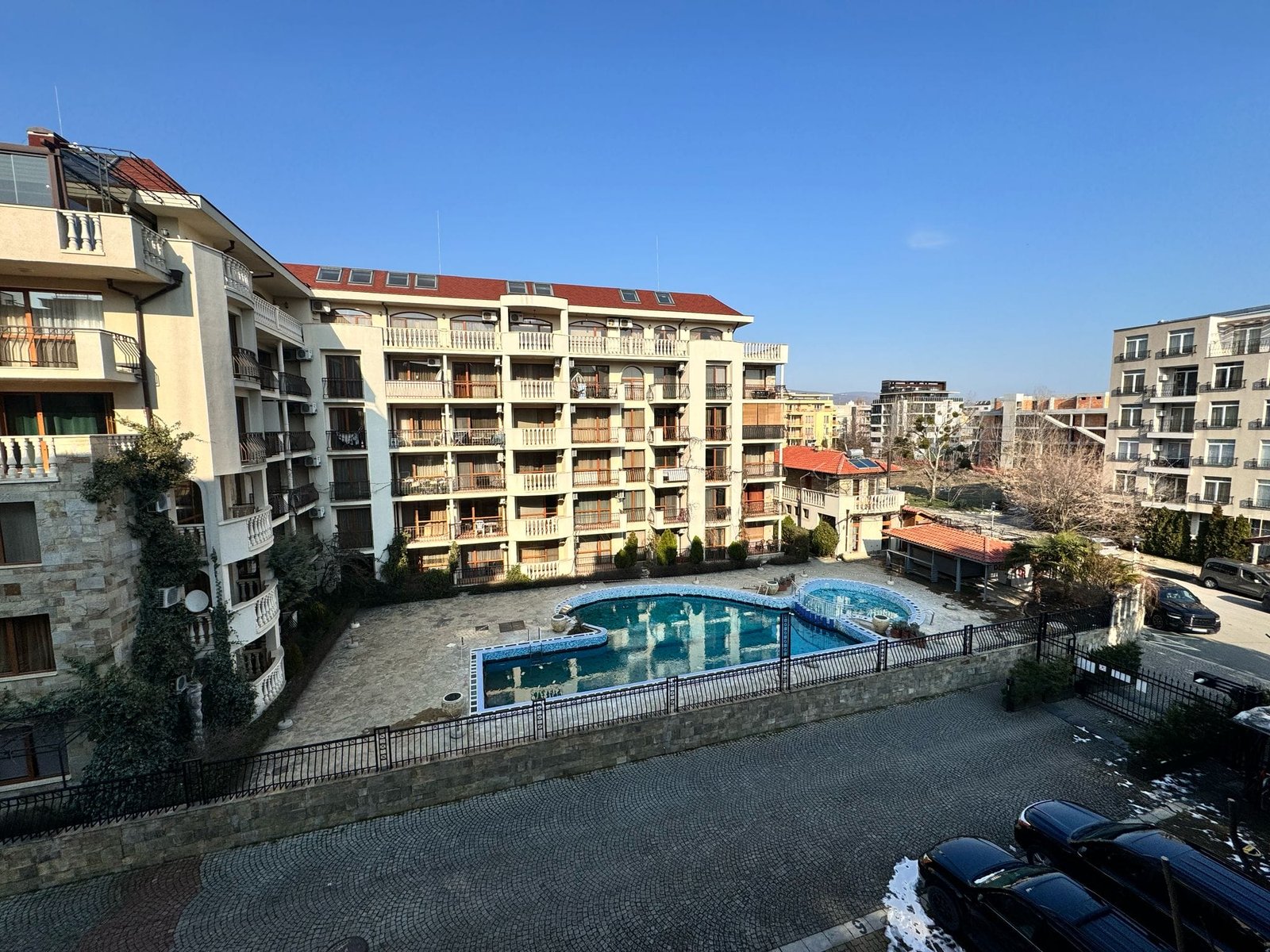 Современный жилой комплекс в Болгарии с бассейном и террасой на фоне ясного неба, идеально подходит для покупки недвижимости.