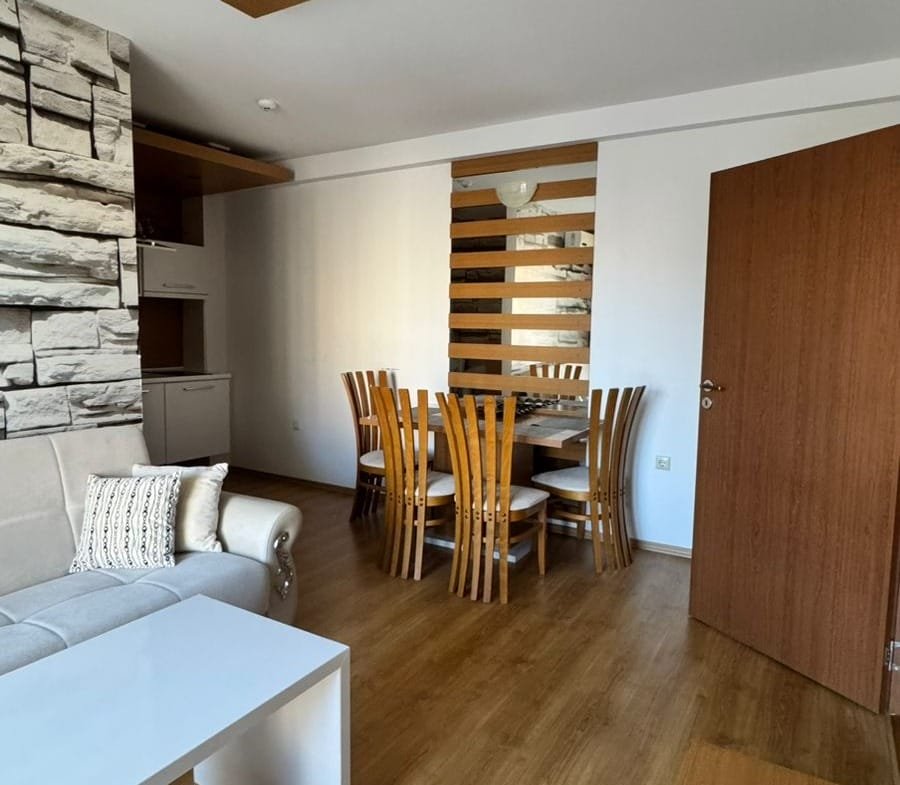 Современный интерьер квартиры в Болгарии с деревянным полом, столом из шести стульев и стильной мебелью.