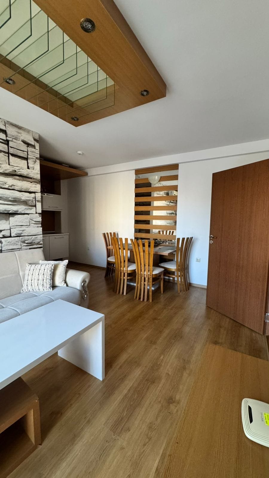 Современный интерьер квартиры в Болгарии с деревянным полом, столом из шести стульев и стильной мебелью.