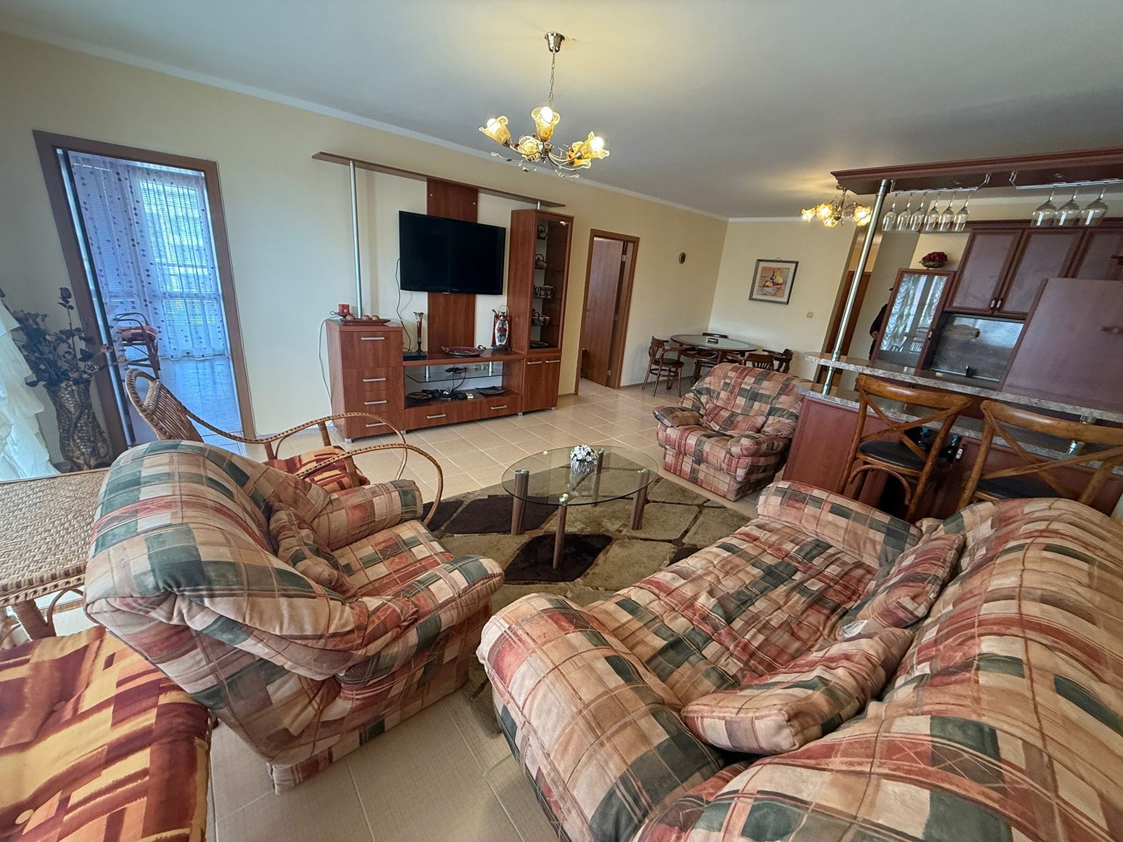 Уютная гостиная с красочными креслами, телеком и кухонным баром, подходит для продажи недвижимости в Болгарии.