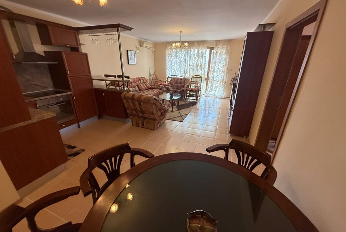 Современная квартира в Болгарии с уютной гостиной, кухней и столовой, оформленной светлыми тонами и комфортной мебелью.