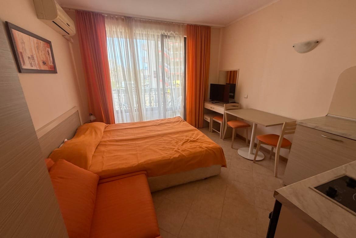 Комфортная квартира в Болгарии с ярким интерьером, большим окном, кухонным уголком и уютной обстановкой для отдыха.