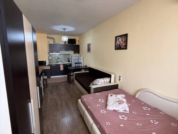 Однокомнатная студия с кухней, светлыми стенами и современной мебелью, окно с видом на улицу.