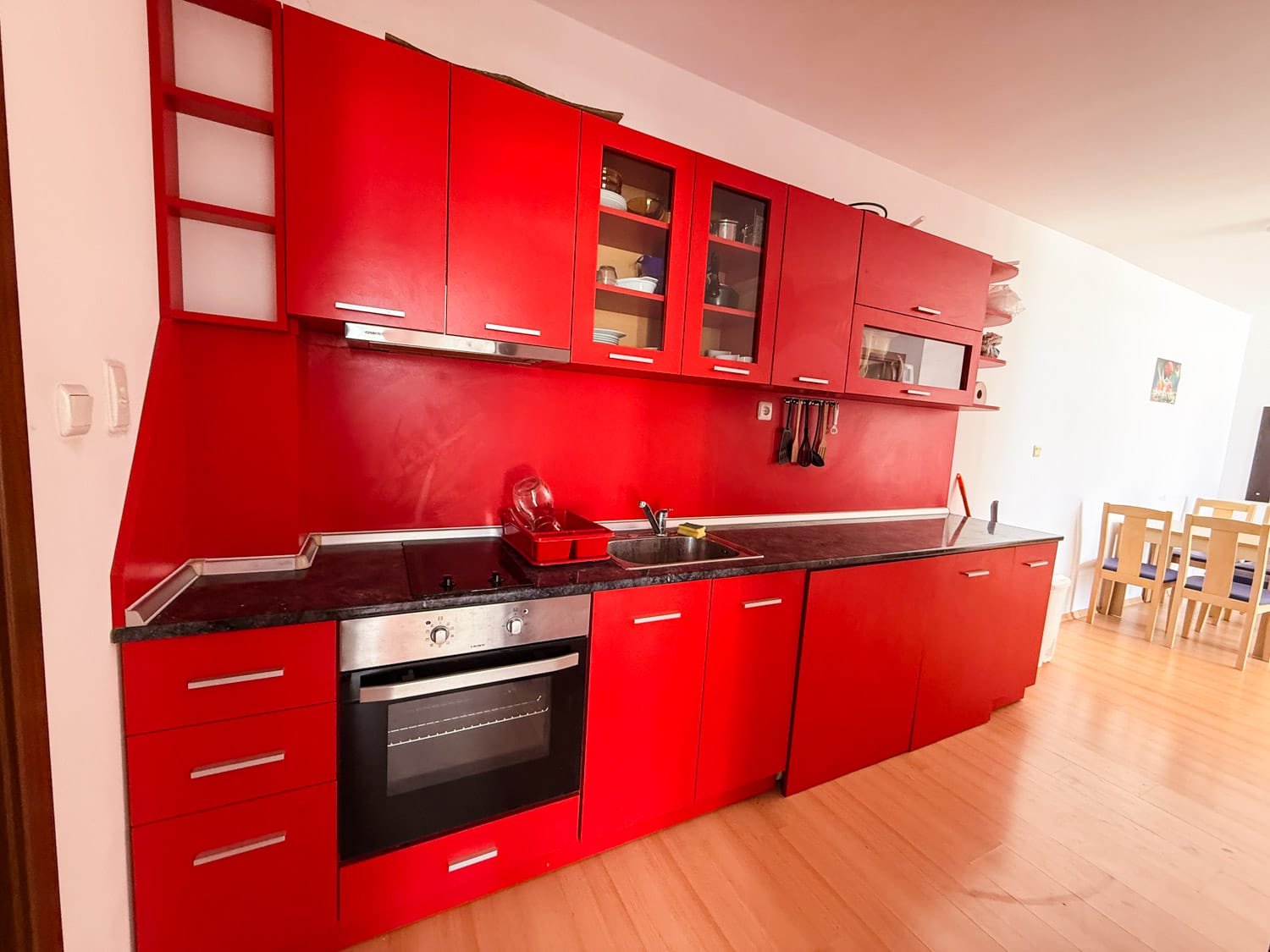 Яркая кухня с красными шкафами и черной столешницей, идеально подходит для покупки недвижимости в Болгарии.