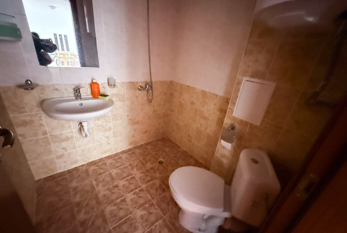 Светлая ванная комната с унитазом, раковиной и душевой кабиной, оформленная плиткой в нейтральных тонах.