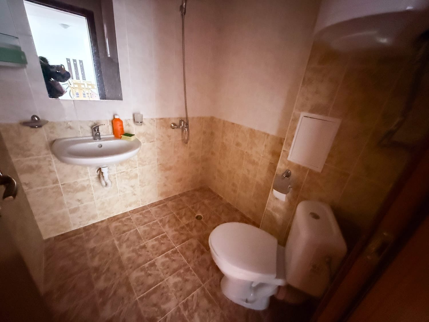 Светлая ванная комната с унитазом, раковиной и душевой кабиной, оформленная плиткой в нейтральных тонах.