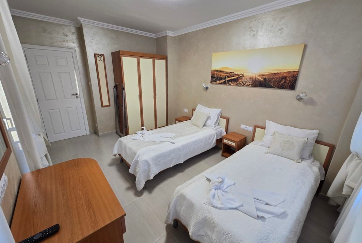 Светлая комната с двумя односпальными кроватями, комодом и шкафом, идеально подходящая для отдыха в Болгарии.