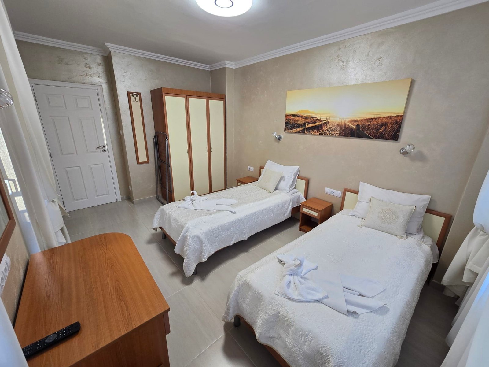 Светлая комната с двумя односпальными кроватями, комодом и шкафом, идеально подходящая для отдыха в Болгарии.