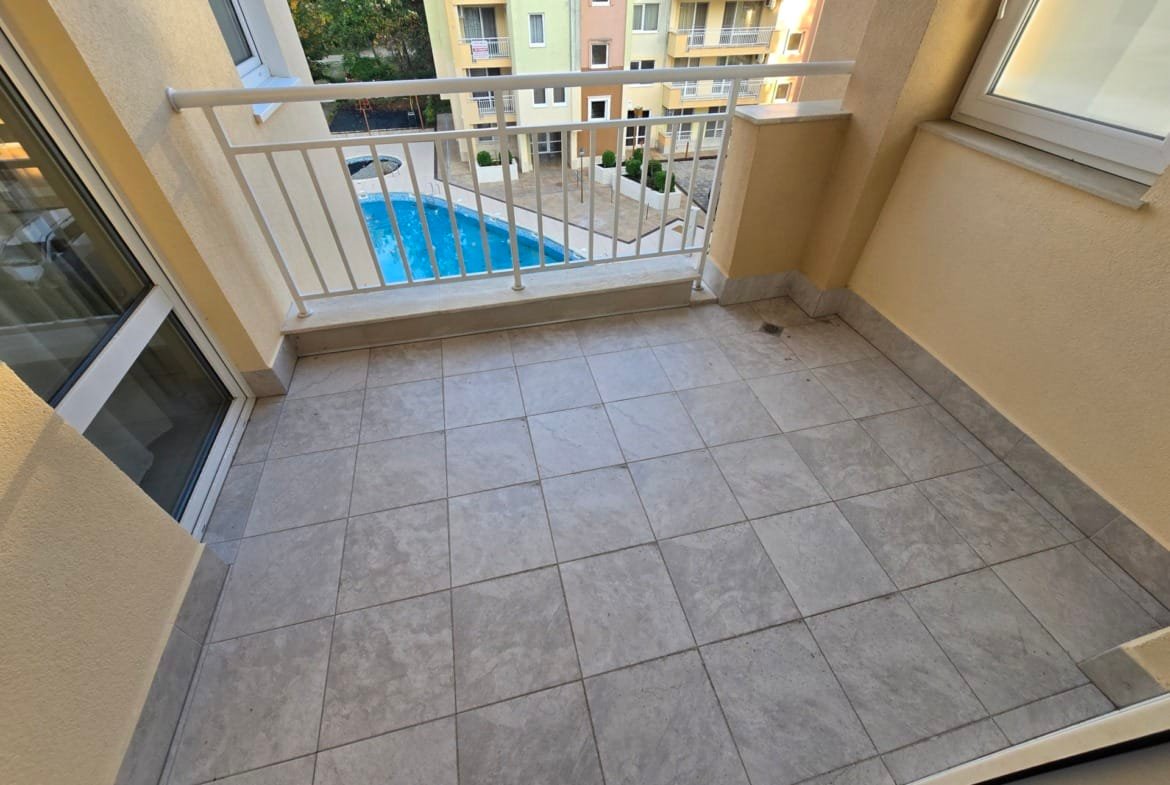 Балкон с плиткой, выходящий на бассейн и жилые комплексы в Болгарии, подходит для продажи недвижимости у моря.