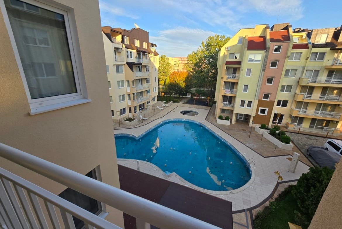 Бассейн с чистой водой и жилые дома в Болгарии, окруженные зелеными насаждениями, идеальные для инвестиций в недвижимость.