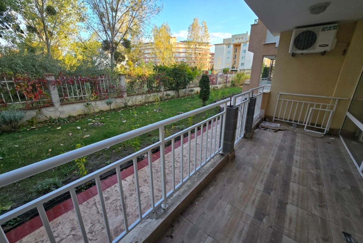 Балкон с видом на зелёный сад в Болгарии, уютное место для отдыха и наслаждения природой рядом с жилыми комплексами.